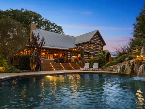 Float in the waterfall pool at dusk while the cabin lights come on.