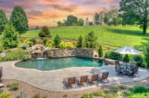 Slide into the private pool while the waterfall pours beside you — rolling green hills at the edge, not another rooftop in sight.