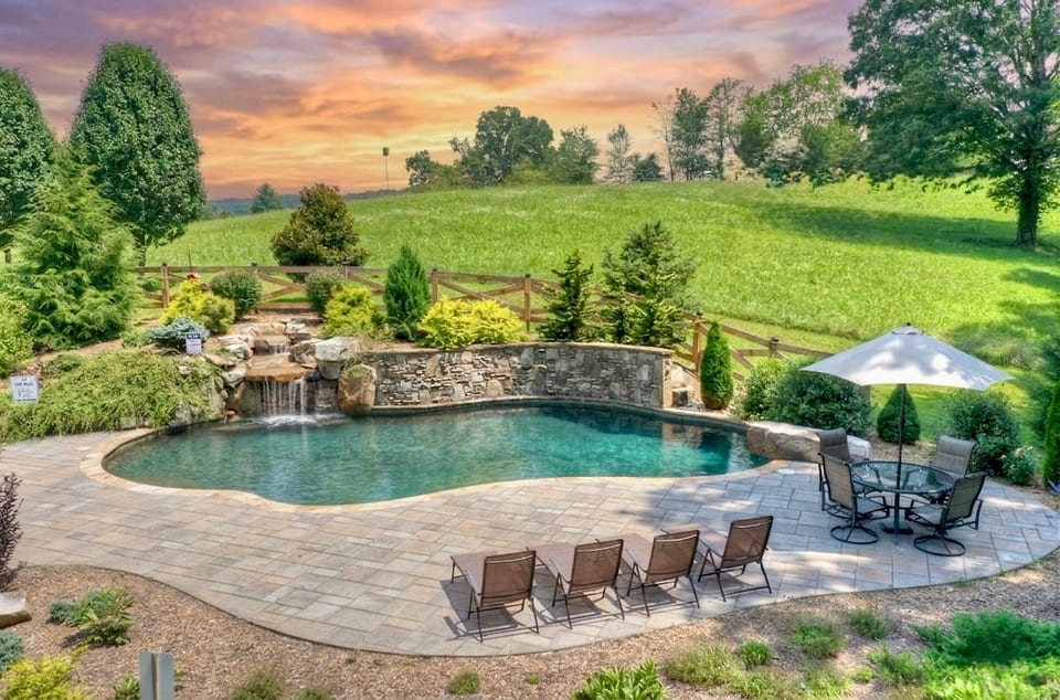 Slide into the private pool while the waterfall pours beside you — rolling green hills at the edge, not another rooftop in sight.