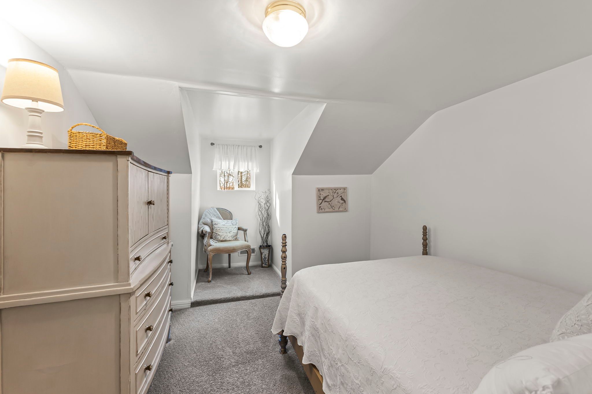 Full size bed with dresser and cozy nook with chair. 