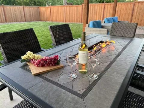 Enjoy a beautiful time outside with a fenced backyard, covered patio, green grass, and the table fire pit.
