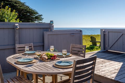 A teak dining table within the private courtyard offers an open view toward the oceanfront, creating an effortless setting for unhurried meals with the bluff trail just beyond.