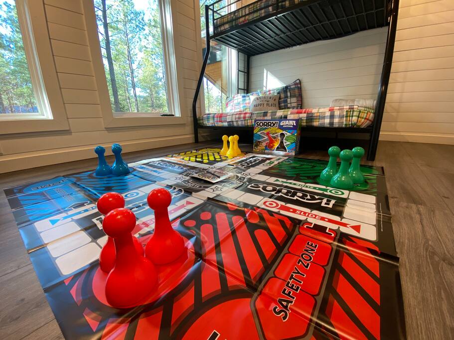 Giant Sorry! game with vibrant pawns, plaid bedding, and cozy wooden interiors.

