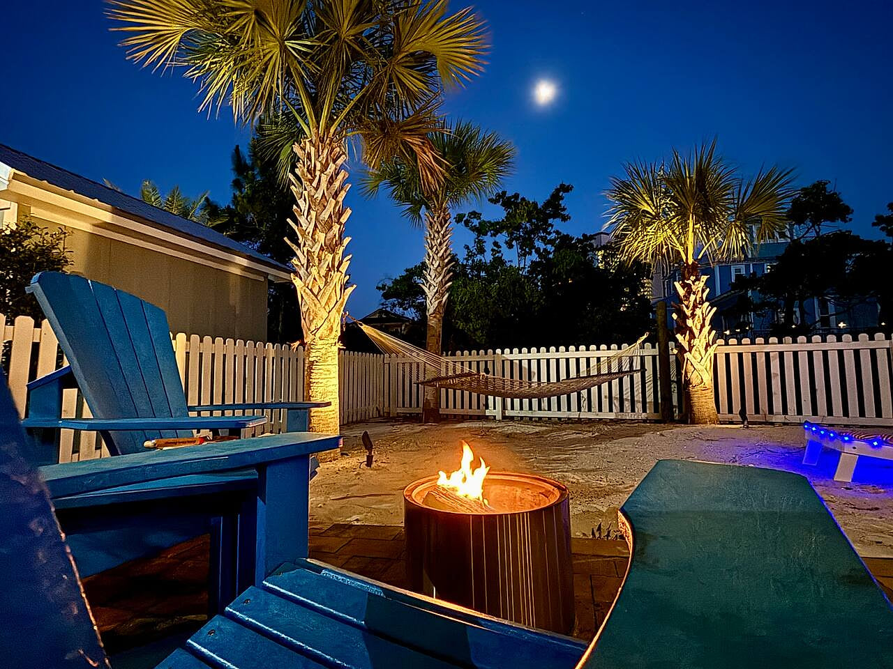Moonlit backyard escape: fire pit, hammock, and glowing palms for ultimate relaxation.