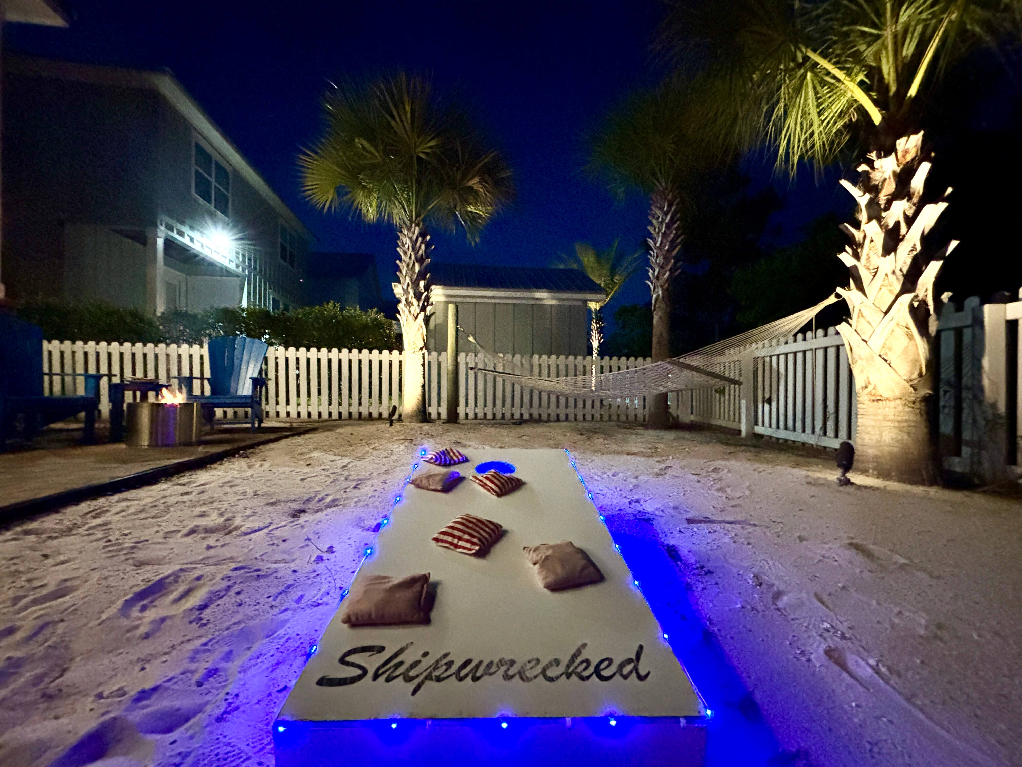 Relax under glowing palm trees, cozy chairs, and a fire pit for perfect backyard serenity.
