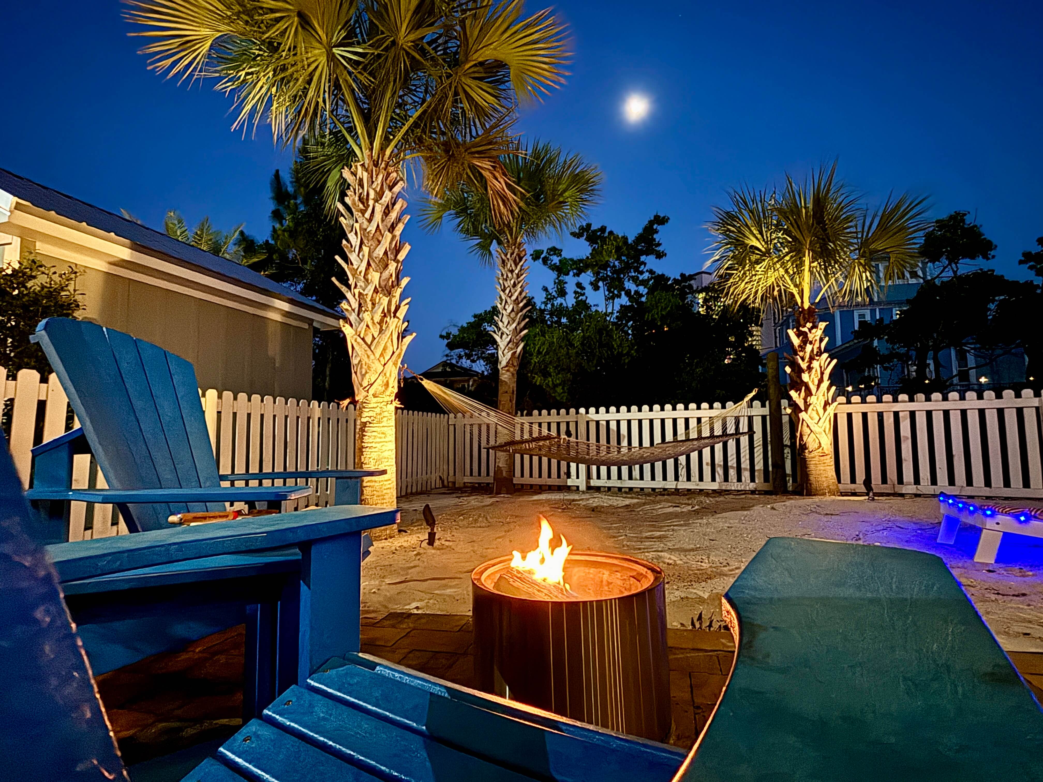 Moonlit backyard escape: fire pit, hammock, and glowing palms for ultimate relaxation.
