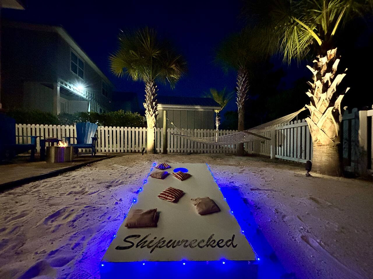 Relax under glowing palm trees, cozy chairs, and a fire pit for perfect backyard serenity.

