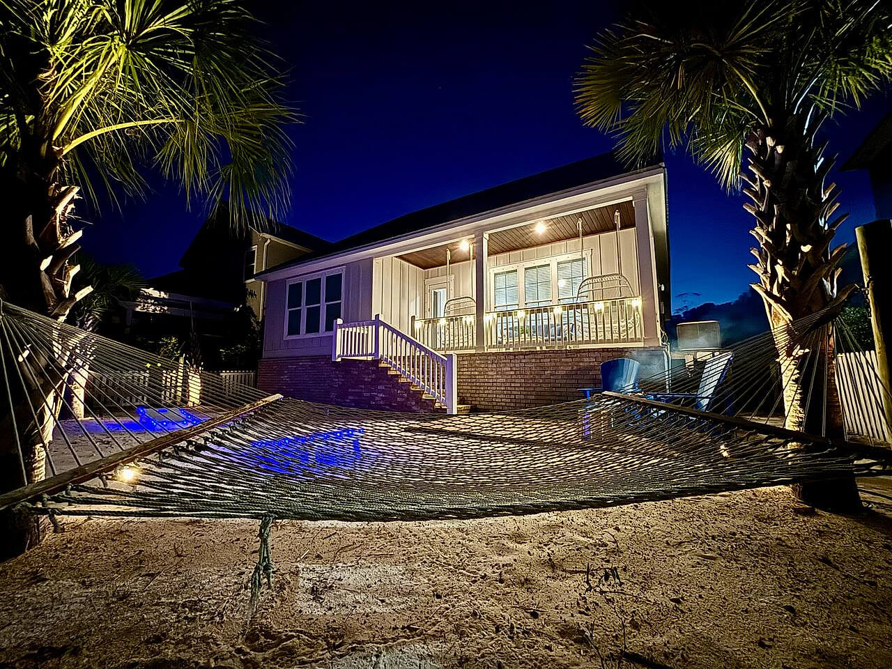 Lounge by twilight: hammock sways, palm silhouettes, and beach house glow for dreamy vibes.

