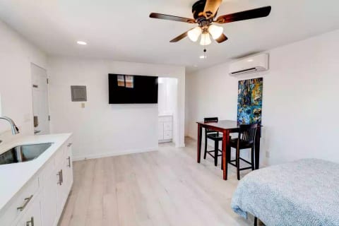 Open Studio Layout with Full Size (Double) Bed, Mounted 55" Roku TV, Full Fridge/Freezer, Mini 24" Range Stovetop w/ Oven, Microwave, and Dining Table w/ Chairs.