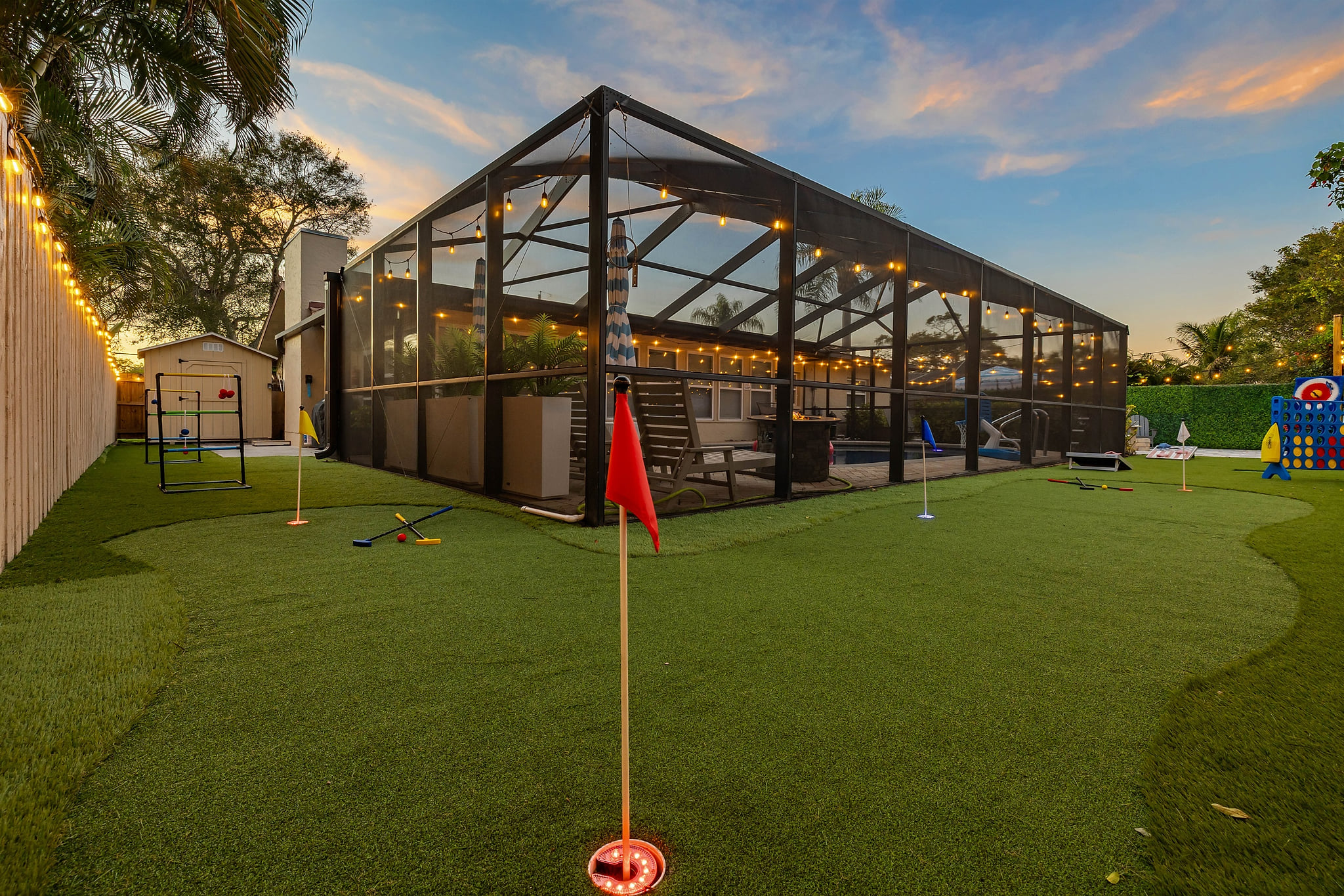 A fun outdoor game area for adults and kids alike, featuring putt putt golf, ladder ball, axe throwing, giant Connect 4, and cornhole. Cozy string lights create a welcoming vibe, perfect for family fun, friendly competition, and relaxing evenings.