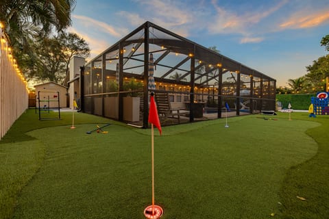 A fun outdoor game area for adults and kids alike, featuring putt putt golf, ladder ball, axe throwing, giant Connect 4, and cornhole. Cozy string lights create a welcoming vibe, perfect for family fun, friendly competition, and relaxing evenings.