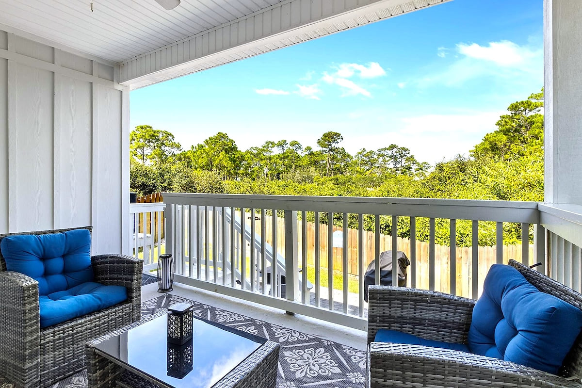 Covered porch with cushioned seating, treetop views & grill.