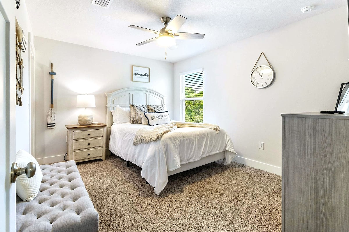 Bright, cozy bedroom with queen bed, ceiling fan, and serene views