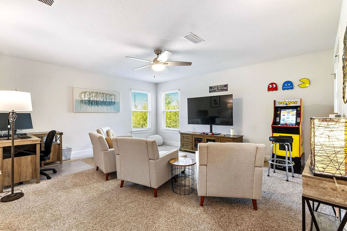 Sunny loft game room with arcade, big-screen TV, and workspace