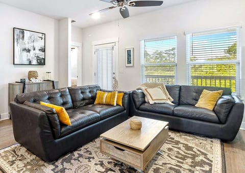 Sunlit living room with leather sofas, balcony views, and cozy style