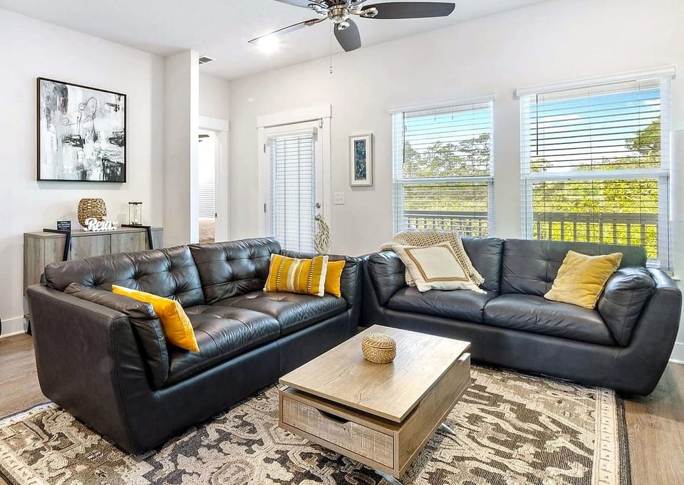 Sunlit living room with leather sofas, balcony views, and cozy style