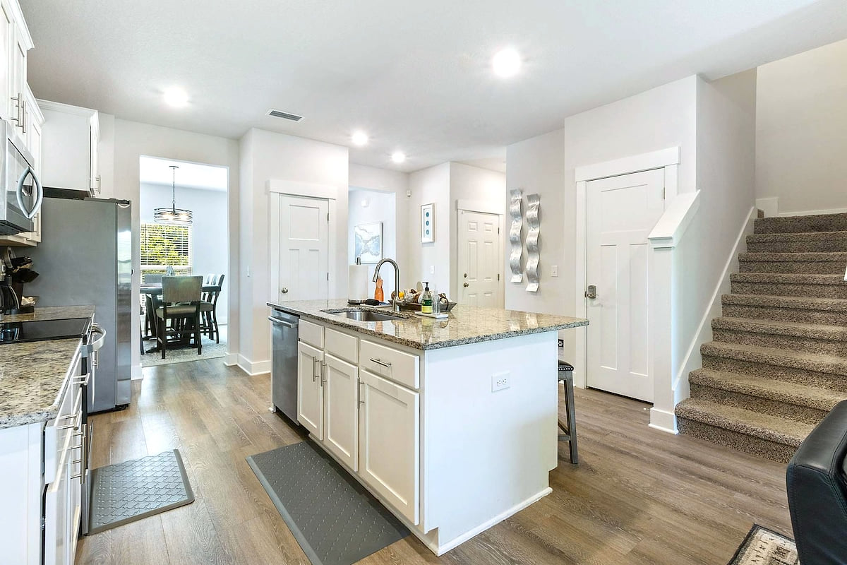 Bright kitchen with granite island, stainless appliances, and open dining