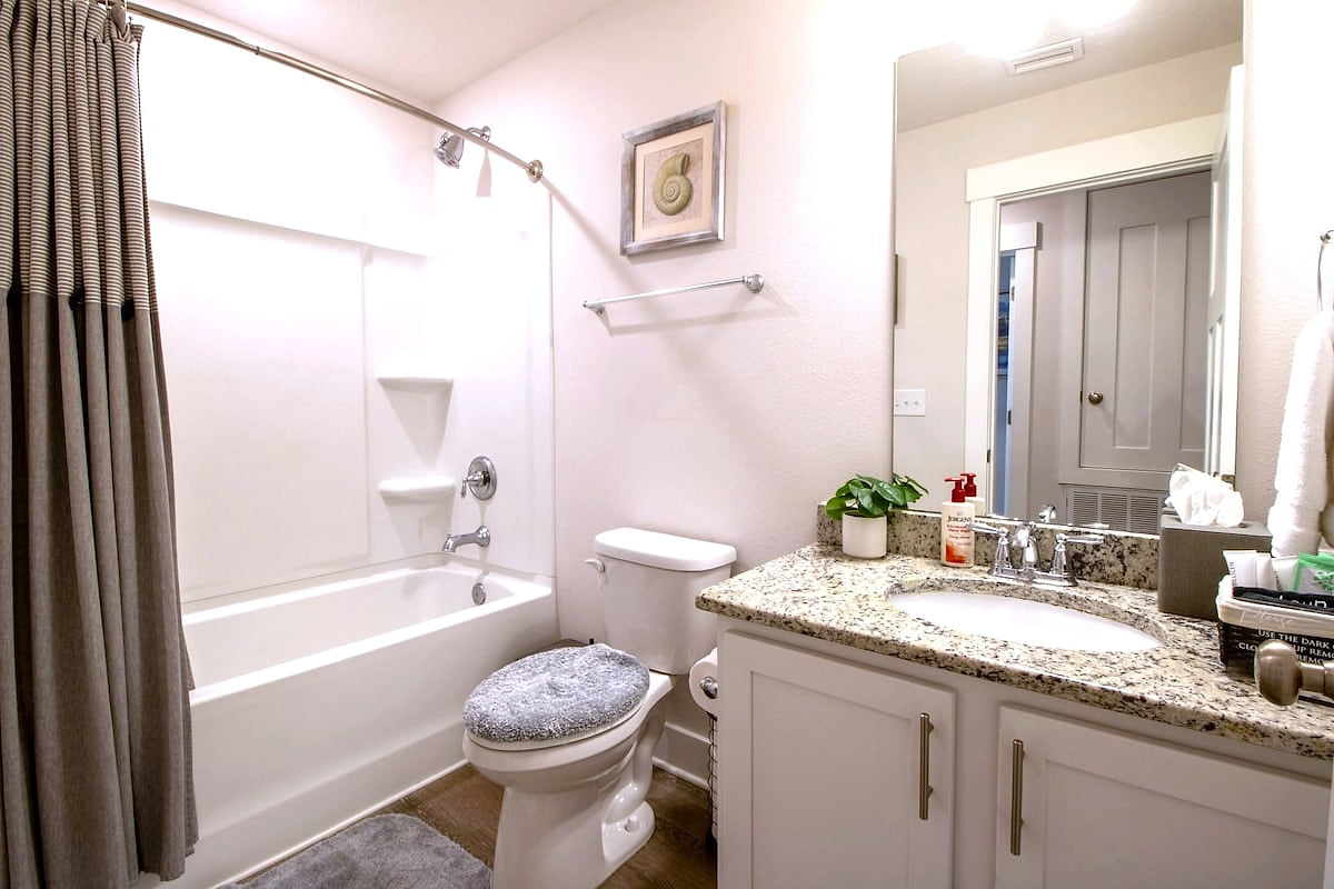 Bright bath with granite vanity, tub/shower & fresh toiletries