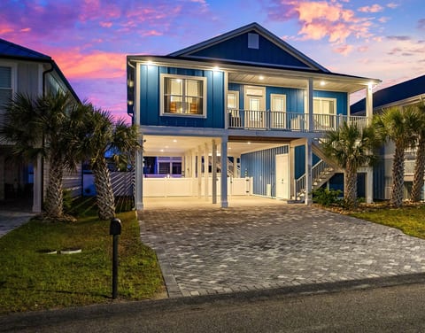 Front of the home lit up at night, welcoming you after a day at the beach.