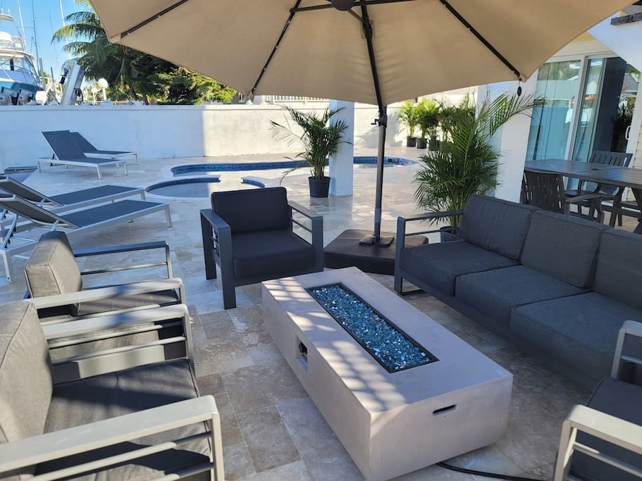 Fire table and sitting area near pool watching boats pass through canal.