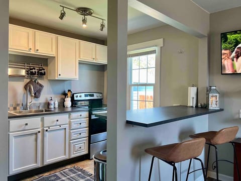 Light and bright kitchen in shades of cream and gray with stainless steel accents and appliances. Coffee is provided for the drip coffeemaker and there is an electric water kettle for tea.