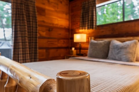 Bedroom 1: Drift off in a log-frame bed wrapped in forest views.