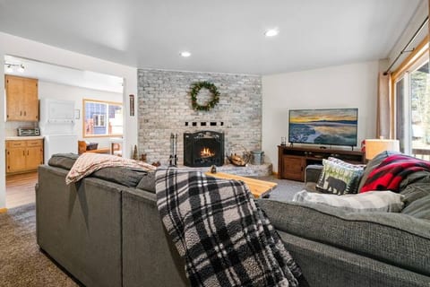 Living room with wood burning fireplace, comfy sectional couch, and 55" Smart TV 