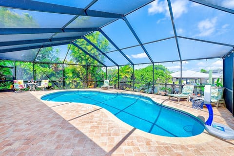 Sunlit pool within a screened enclosure, surrounded by lush landscaping—perfect for a refreshing swim or sunbathing