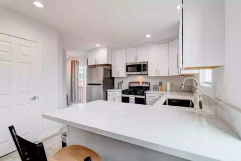 Kitchen with Full Fridge/Freezer, Range Stovetop w/ Oven, Dishwasher, Dining Counter, and Common Area Half-Bath
