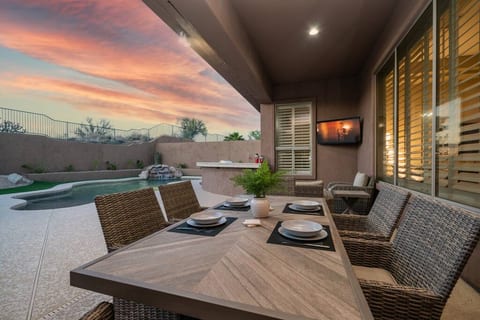 Backyard oasis featuring a private pool, on-site golf putting green, outdoor kitchen with grill, pool loungers, misters, foggers, and an outdoor dining table and seating area.