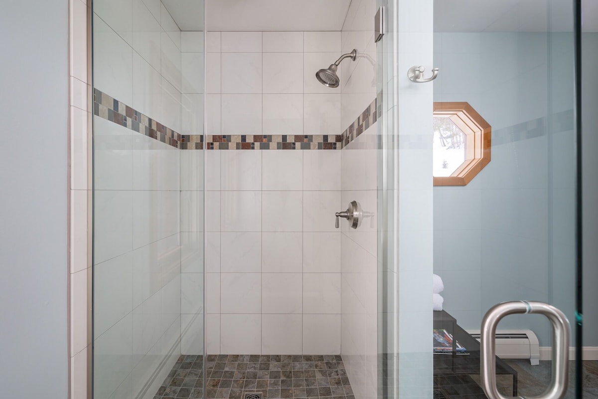 The downstairs full bathroom has ample lighting and a large tiled shower. The downstairs full bathroom has ample lighting and a large tiled shower. - Modern Retreat ~ Stunning Mountain View ~ Hot Tub! - Stowe