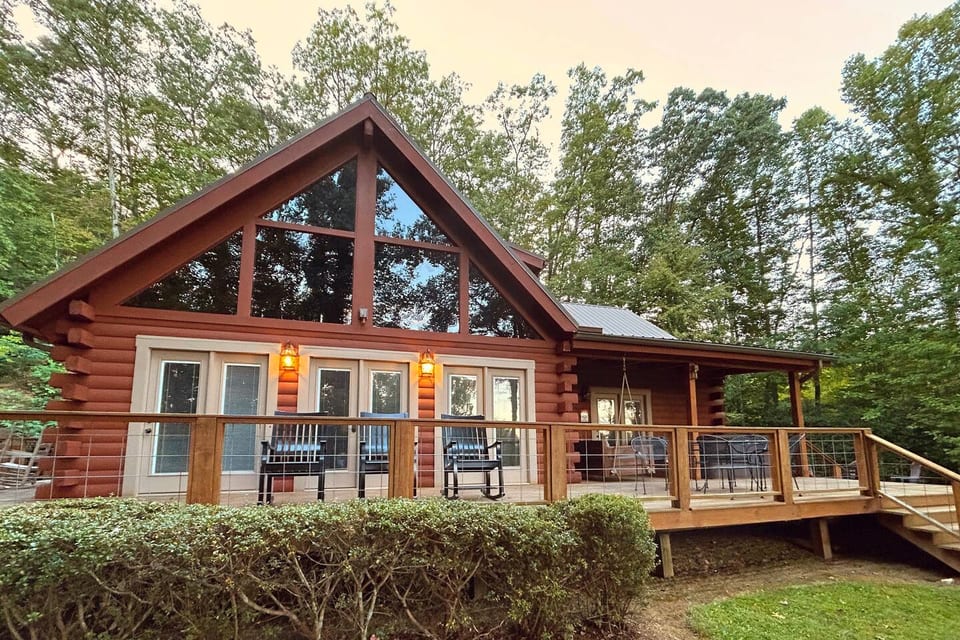 Spacious outdoor deck featuring a variety of seating options including a dining set, couch swing, and rocking chairs, with beautiful views and plenty of space to relax and entertain.