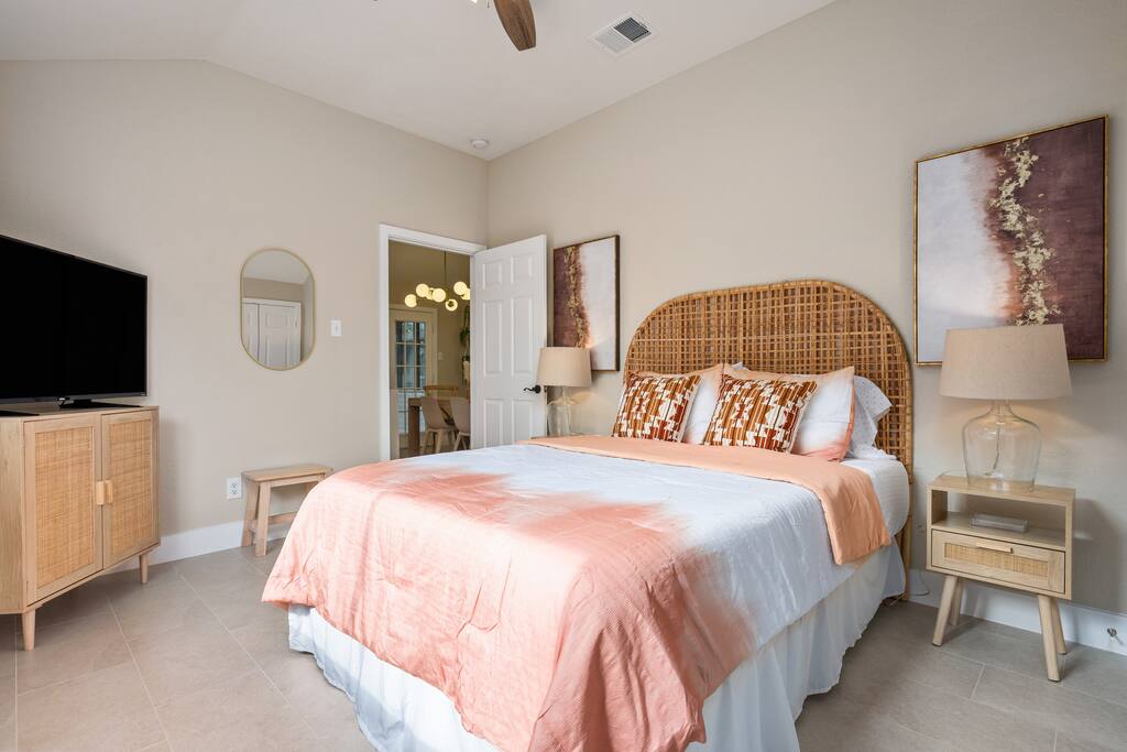 A modern queen bed with a touch of art, cozy lamps, and a TV for added relaxation