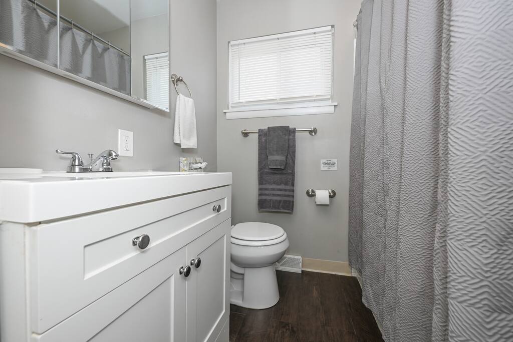 Bathroom - 1st floor hallway; single sink, vanity, medicine cabinet, toilet, tub w/ shower - Dan Street Bungalow: 3 BR & 1 BA, A/C & laundry - Akron