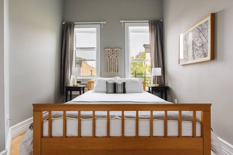 Master Bedroom - Queen size bed with window AC unit. Bedside lamps with charging outlets on the base. Located in the front of the building.