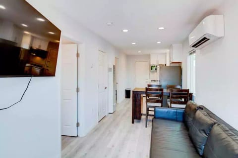 Open Concept Kitchen with Full Fridge/Freezer, Range Stovetop (Stove Only, NO OVEN), Air Conditioning (AC), Dining Table, 55" Wall Mounted Roku TV, Sofa (converts flat to full size bed), and Common Area Half-Bath