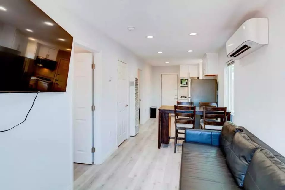 Open Concept Kitchen with Full Fridge/Freezer, Range Stovetop (Stove Only, NO OVEN), Air Conditioning (AC), Dining Table, 55" Wall Mounted Roku TV, Sofa (converts flat to full size bed), and Common Area Half-Bath
