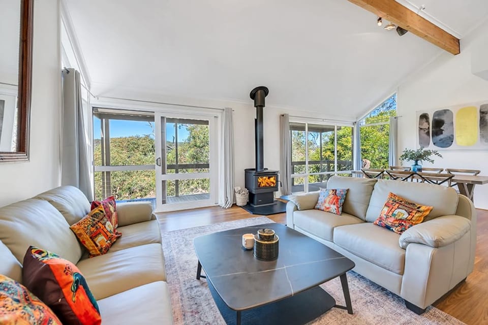 Living room with high ceilings offering views of Mount Lofty and a balcony. The lounge area also includes a dining space and a fireplace, perfect for cozying up during the winter months.