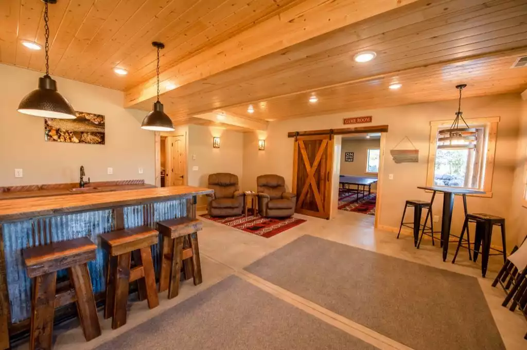 Bar area with TV, recliners, copper sink and beverage fridge. Barn door to new game room.