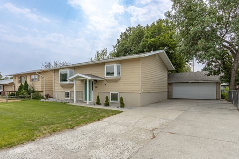 Spacious split-level home with large driveway, garage, and shady yard