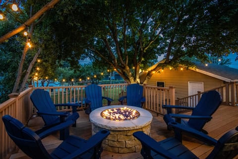 Cozy fire pit deck with string lights and Adirondack seating