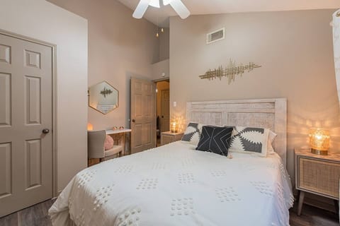 A peaceful second bedroom offering a queen-size bed, side lamp for soft lighting, ceiling fan for a cool breeze, and a dressing area with a mirror