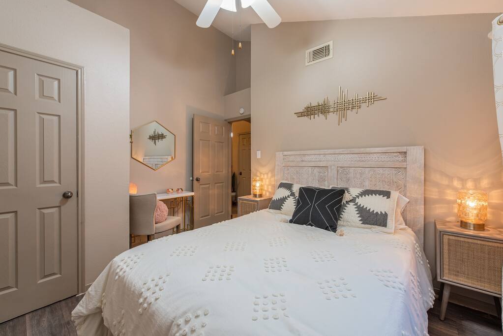 A peaceful second bedroom offering a queen-size bed, side lamp for soft lighting, ceiling fan for a cool breeze, and a dressing area with a mirror