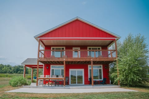 Bright red country home with balcony, patio, and golf course view