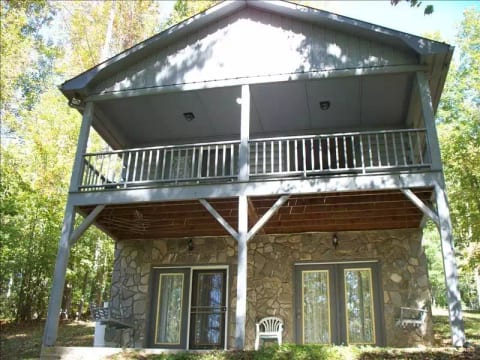 Back view of cabin with swings and chairs for relaxation facing the woods.