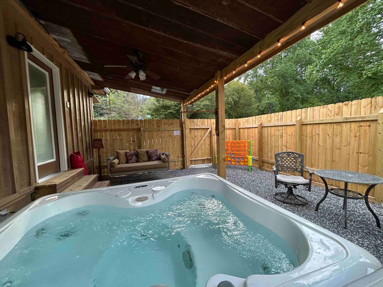 Private Hot Tub in a fully fenced-in backyard. Enjoy this relaxing spot after hiking in the Great Smoky Mountains or exploring downtown Bryson City, North Carolina. This area also includes fun 2-player games, a porch swing, and outdoor seating.