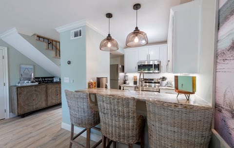 Modern kitchen with wicker bar stools, pendant lights, and stainless appliances—perfect for family dining.