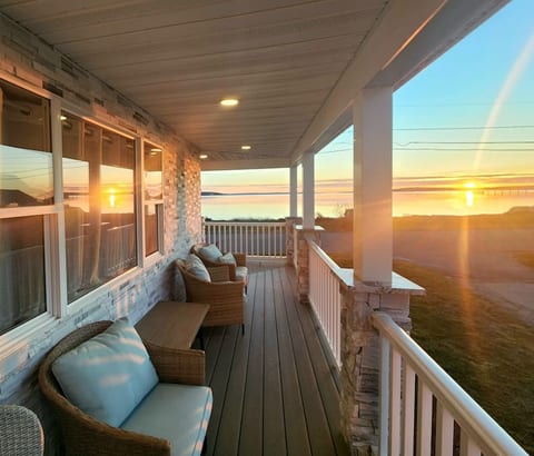 Relaxing porch furniture invites you to unwind in the midst of nature's spectacle. Sunset drenching the waterfront in warm hues, casting a golden glow. Enjoy a refreshing beverage by the water's edge as the sun bids adieu for today.
