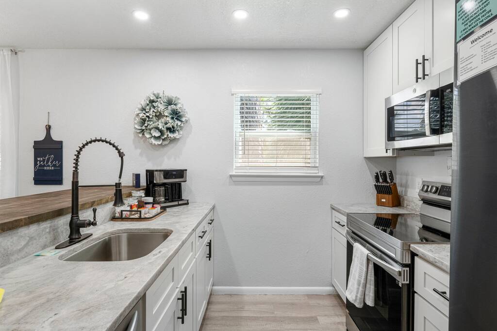 The kitchen is well-equipped with modern stainless steel appliances, including a microwave, electric stove, and oven. Have essential items for your home away from home.