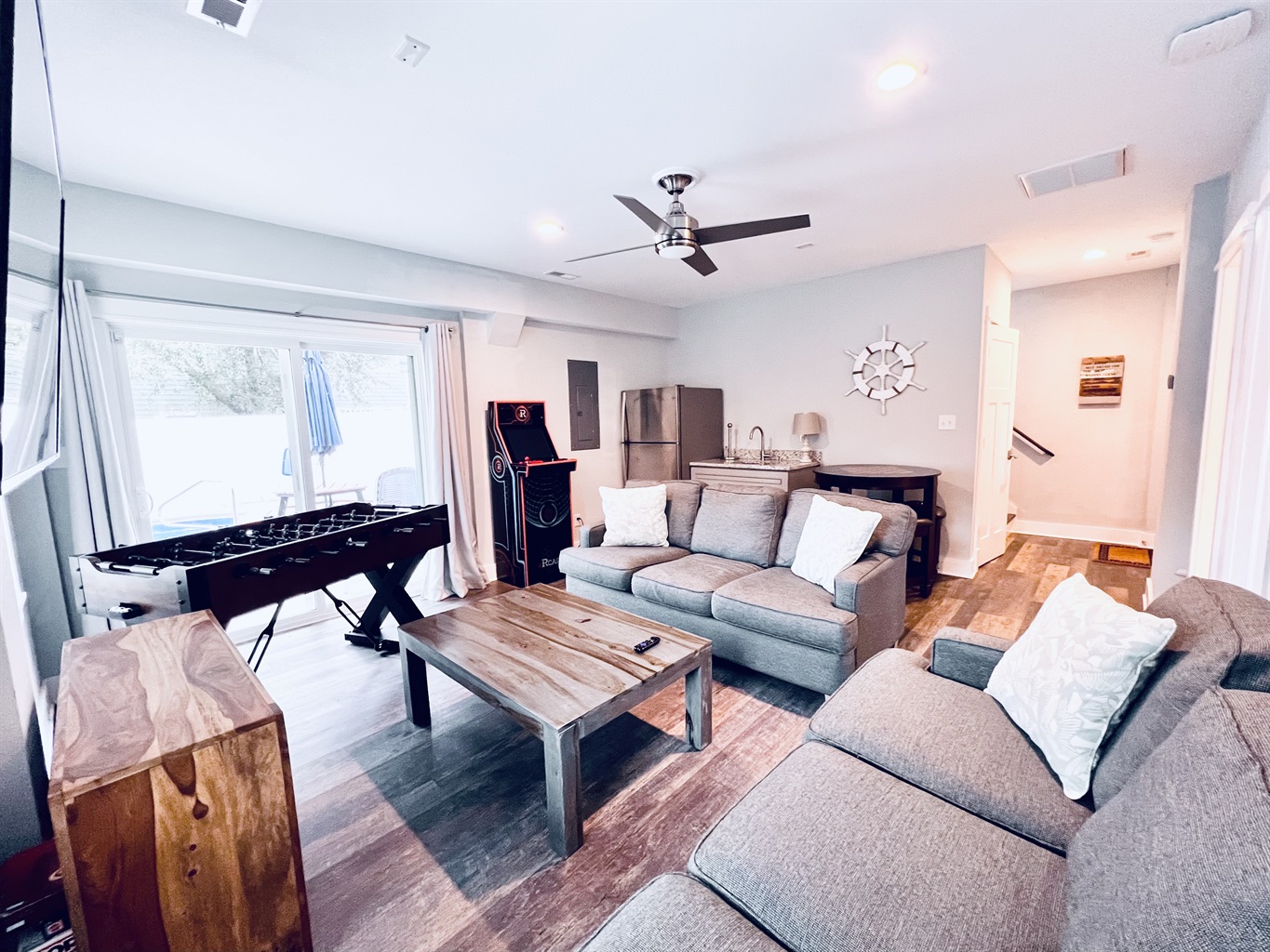 Enjoy fun and games in the open game room featuring a foosball table, inviting sofas, and a classic wooden floor.